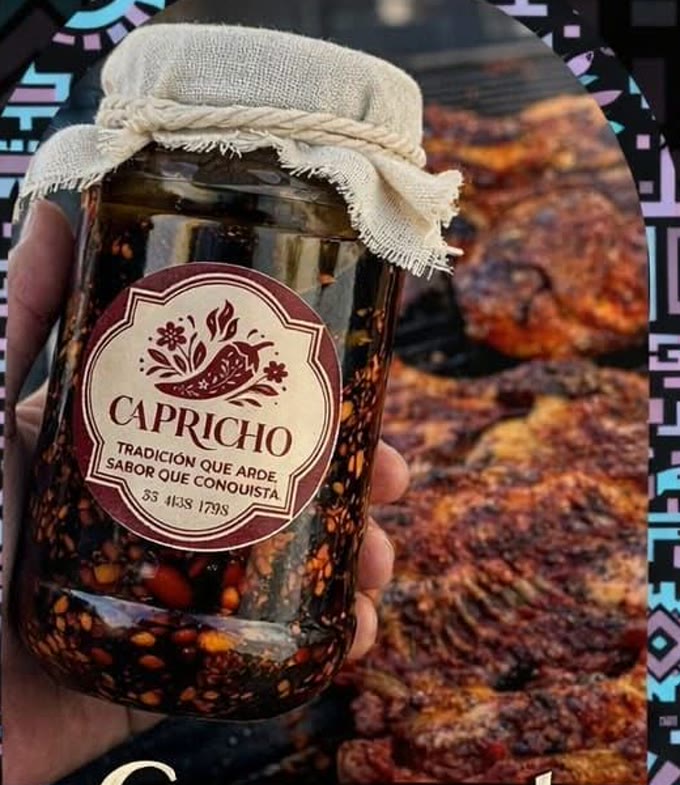 Frasco de salsa macha Capricho, tapa de manta y cordel, junto a una carne asada