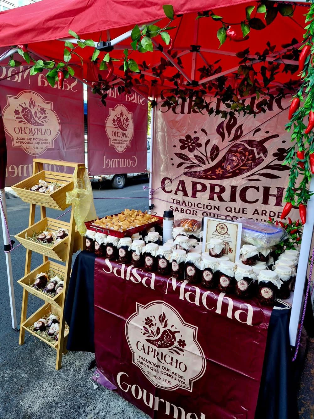 Puesto de Capricho en un tianguis, con frascos de salsa macha y lonas de la marca